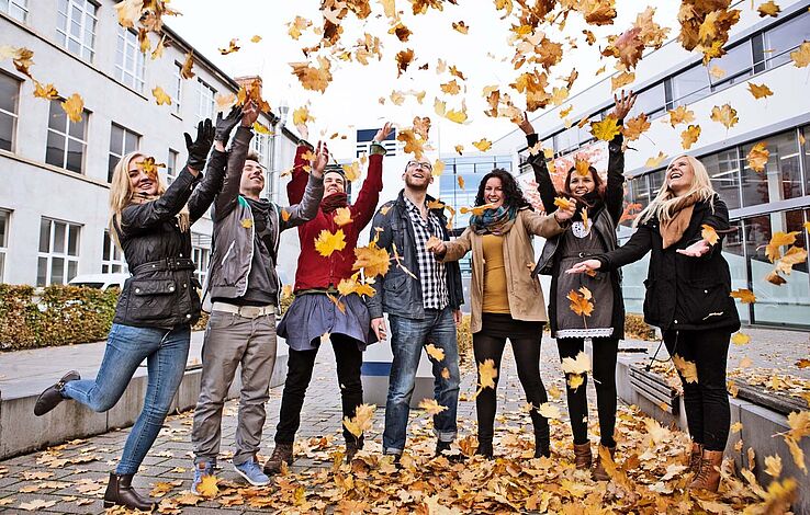 Gruppe Studierende stehen vor der FH im Herbst