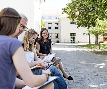 Gruppe Studierender sitzt auf dem Campus